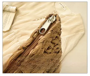 Detailed close-up of the smooth metal zipper on a brown woven straw beach shoulder bag