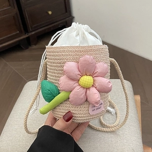 Mini hand-woven straw bucket bag with pink floral decoration and drawstring closure