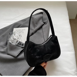 Dettaglio borsa sottobraccio minimalista in pelle nera con texture vintage e zip argento