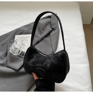 Dettaglio di una borsa sottobraccio nera a mezzaluna in pelle con texture marmorea