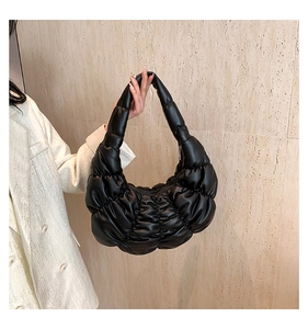 Detailed view of black pleated dumpling bag with soft quilted texture and shoulder strap