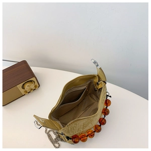 Detail van de mosterdgele crossbodytas met amberkleurige kralen en binnenzak