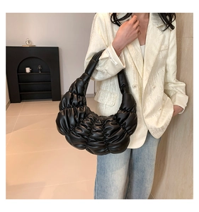 Close-up of black pleated cloud bag in shiny faux leather with soft textured details