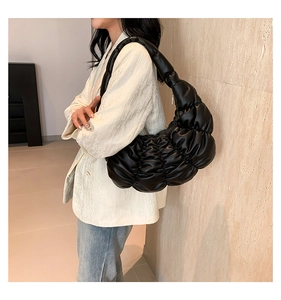 Close-up of black ruched cloud bag showing glossy PU leather texture and pleated design