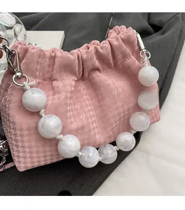 Close-up of pink cloud bag with beaded handle showing textured houndstooth fabric