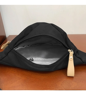 Vue intérieure du sac de poitrine en toile noire montrant la doublure et la poche zippée