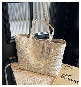 Detailed view of woven tote bag texture with elegant scarf accessory on handle