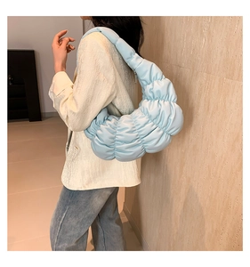 Side view of light blue pleated cloud bag showing soft padded texture and crescent shape