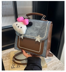 Detail of blue denim and brown leather handbag with star studs and plush dog charm