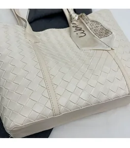 Detailed close-up of the woven leather texture and printed silk scarf on the beige tote bag