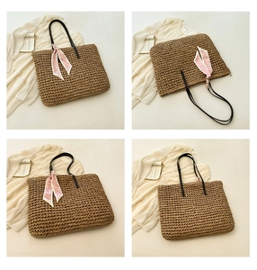 Detail of woven straw tote bag with black handles and pink floral scarf decoration