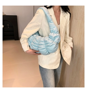 Light blue pleated dumpling bag shown on a model's shoulder for casual chic style