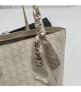 Detailed close-up of woven cream leather tote bag featuring a decorative silk scarf handle