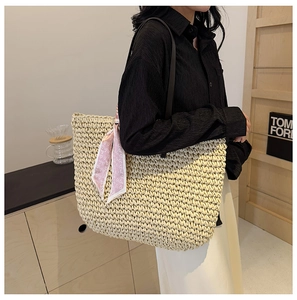 Detail of large straw beach bag with leather shoulder strap and pink heart scarf decor
