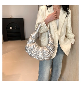 Detail of silver pleated cloud bag with metallic finish shown on model in street style