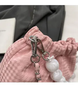 Detail of pink drawstring bag with houndstar texture and beaded silver chain strap