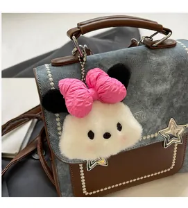 Detail of blue denim and brown leather satchel with star rivets and plush charm