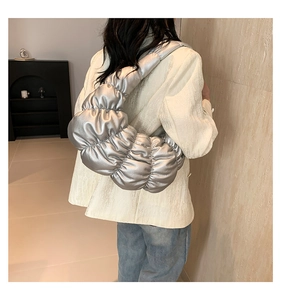 Silver metallic pleated shoulder bag worn with minimalist stylish blazer and blue jeans