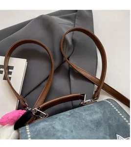 Detail of blue denim crossbody bag with adjustable brown strap and plush heart charm