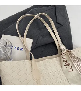 Detail of white woven leather tote bag accented with elegant printed silk scarf