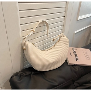 Detail of cream pleated corduroy crescent bag with golden zipper and adjustable strap