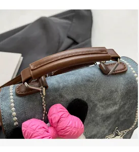 Detail of blue denim handbag with brown PU handles and star metal buckle accent