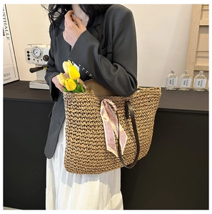 Detail of handwoven straw tote bag with heart pattern scarf and leather handles