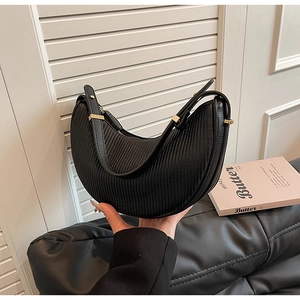 Detail of black pleated crescent bag with adjustable leather strap and golden hardware