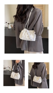 Detail of white pleated cloud bag featuring pearl handle and fine metal chain strap