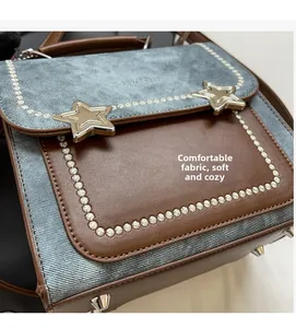 Detail of denim and brown leather bag with metal star studs and white stitching