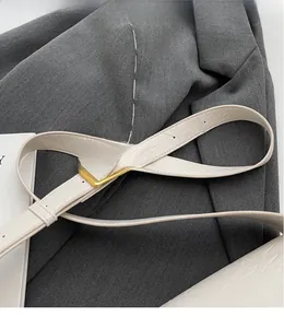 Detail of adjustable cream white shoulder strap with crocodile pattern and gold buckle