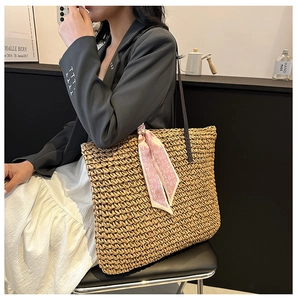 Detail of hand-woven straw tote with pink heart scarf on shoulder, summer beach style