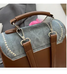 Detail of denim and brown leather bag with silver metallic hardware and rivets