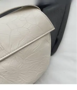 Detailed close-up of off-white pleated leather texture and fine stitching on the bag