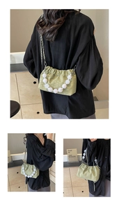 Detail of light green pleated cloud bag featuring large white beads and silver chain strap