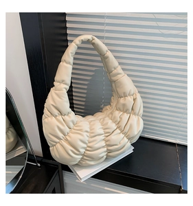 Detail of a creamy white quilted bubble shoulder bag on a minimalist background
