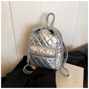 Detail of silver mini backpack featuring quilted texture and metallic bow decoration