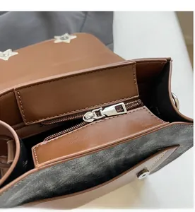 Detail of brown faux leather bag showing inner zipper pocket and star metal buckle