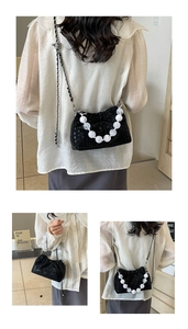 Detail of black pleated cloud bag featuring large marble beads and silver chain strap