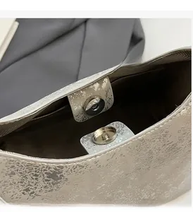 Macro shot of silver textured leather handbag featuring premium magnetic snap hardware