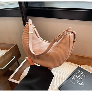 Detail of light pink crescent bag with vertical texture and gold metal hardware accents