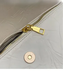 Detailed view of cream leather texture with premium golden hardware and smooth zipper pull