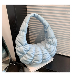 Detailed view of light blue quilted hobo bag with soft pleated texture and crescent shape