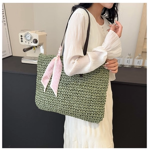 Detail of green straw beach tote bag with brown leather straps and floral silk scarf
