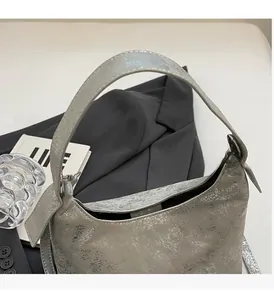 Detail of silver textured leather handbag featuring wide handles and metallic finish