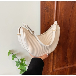 Detail of cream white dumpling bag showing pleated texture and gold metal hardware
