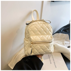 Detail view of cream quilted mini backpack with bow knot decoration and gold hardware