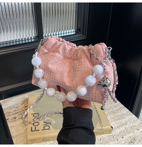 Close-up of pink pleated cloud bag with houndstooth texture and white pearl handle