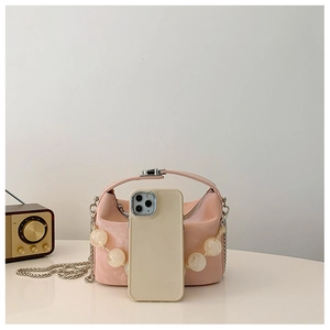 Roze halve maan tas met parelriem en ketting getoond naast een smartphone voor maat