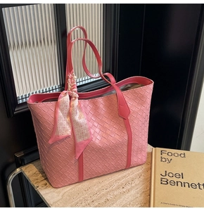 Close-up of pink woven leather tote bag featuring decorative silk scarf on handle